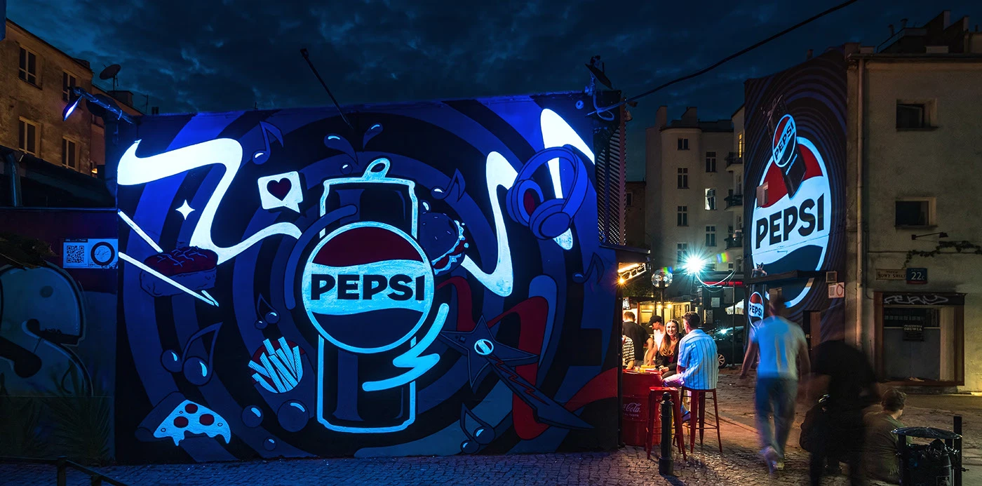 Pepsi mural lit at night with food and music icons
