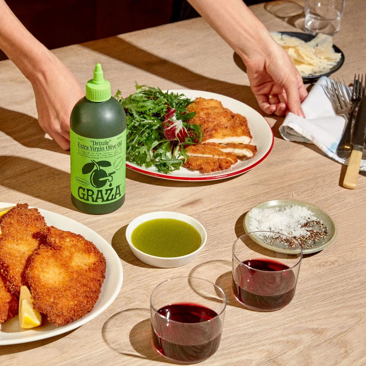 Table with prepared food and a Graza bottle showing the product in use